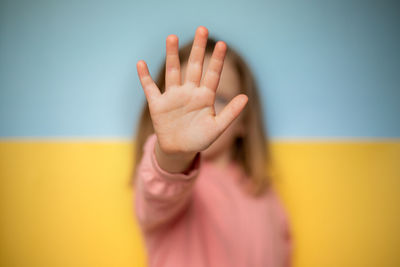 No war in ukraine. stop war. child shows a palm on the background of the ukrainian flag