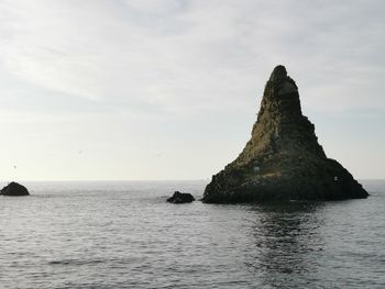 Rock formation in sea against sky