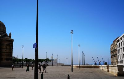 Street amidst buildings against clear blue sky