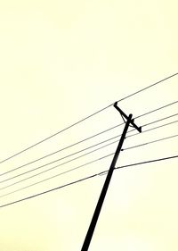 Low angle view of silhouette birds perching on cable against clear sky