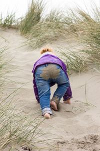 Low angle view of girl crawling on sand at beach