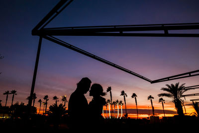 Silhouette couple romancing in park at sunset