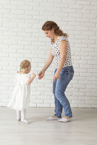 Full length of woman standing against wall