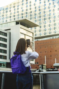 Side view of young woman standing against building