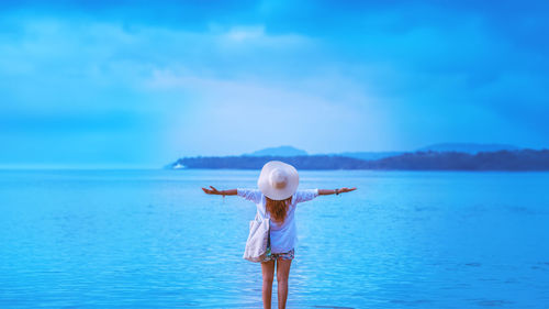 Rear view of woman standing in sea against sky