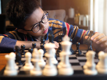 Serious boy wearing eyeglasses while playing chess at home