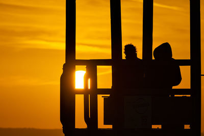 Silhouette people against orange sky during sunset