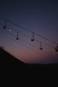 Low angle view of power lines against sky during sunset