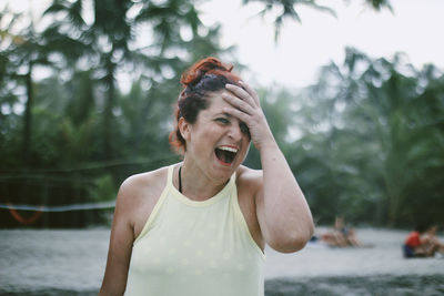 Close-up of mature woman laughing against tree
