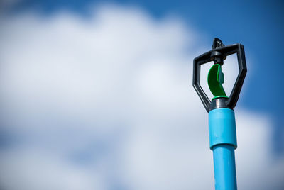 Low angle view of sprinkler against blue sky