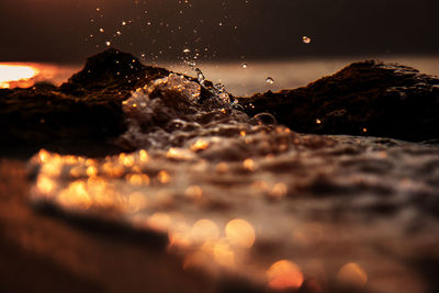 Surface level of rocks on shore against sky at sunset