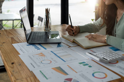 Midsection of businesswoman working on table