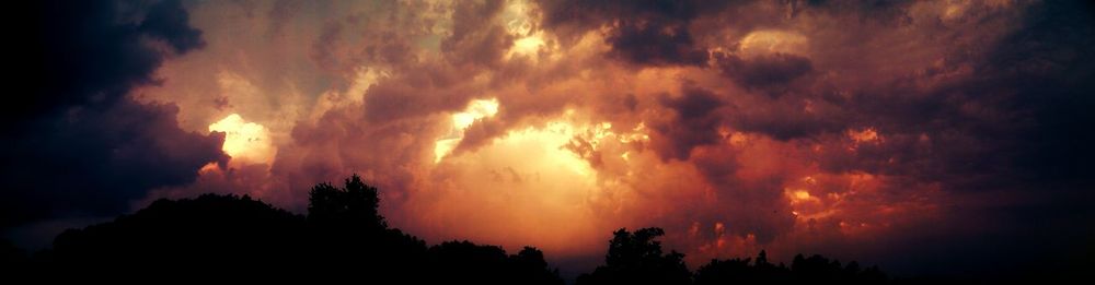 Silhouette of landscape against cloudy sky at sunset