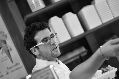 Side view of man looking away while standing in shop