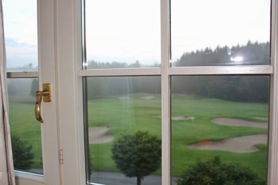 Scenic view of field seen through glass window