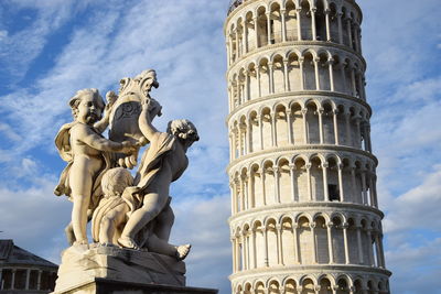 Statue and leaning tower of pisa against sky