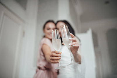 Bridesmaid and bride holding champagne flute