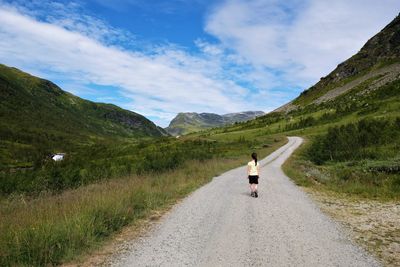 Rear view of woman riding motorcycle on road against sky