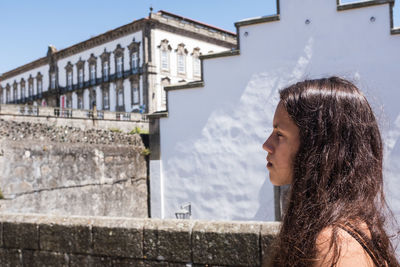 Side view of woman looking through window