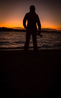 Silhouette man standing on beach against sky during sunset