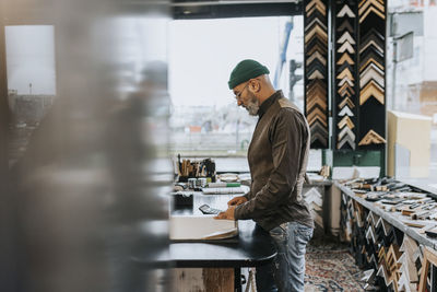 Male entrepreneur standing at workbench in frame shop