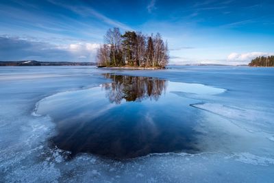 Frozen lake against blue sky during winter
