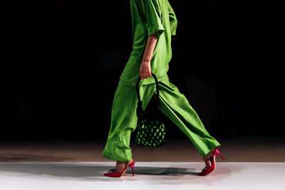 Details of a bright green stylish pants, blouse and red heels. women's elegant casual fashion