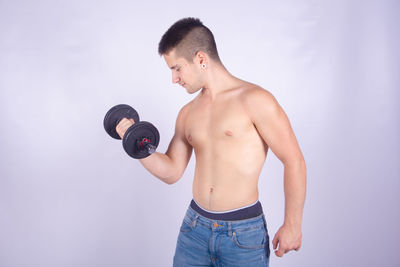 Full length of shirtless man standing against gray background