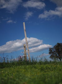 Low angle view of wooden post on field against sky