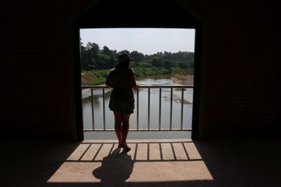 Rear view of woman standing by window