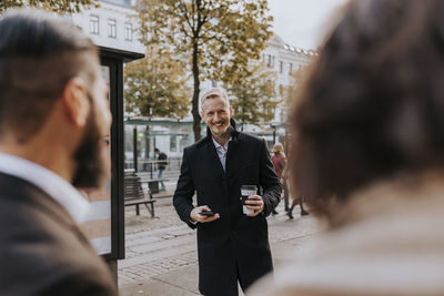 Smiling businessman holding disposable cup