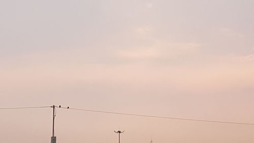 Low angle view of silhouette electricity pylon against sky during sunset