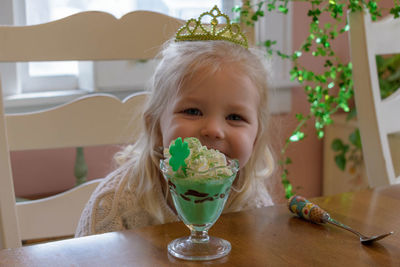 Portrait of cute girl with ice cream on table at home