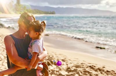 Mother embracing daughter on beach