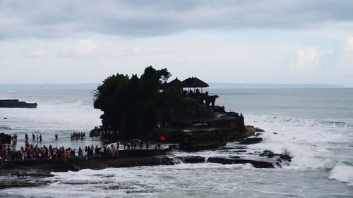 People on cliff by sea against sky