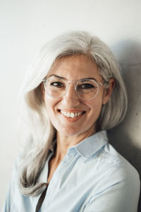 Happiness businesswoman wearing eyeglasses by wall