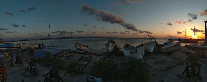 Boats moored on beach against sky during sunset