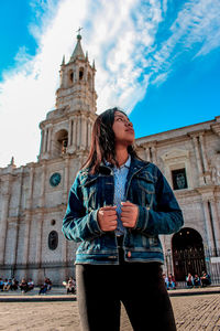 Low angle view of woman looking away while standing against cathedral