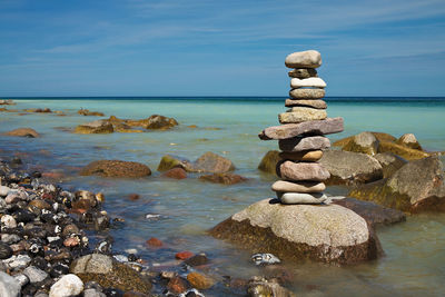 Stack of rocks at beach against sky