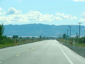Road by mountains against sky