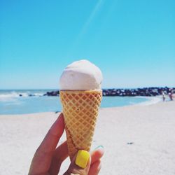 Cropped hand of woman holding ice cream at beach