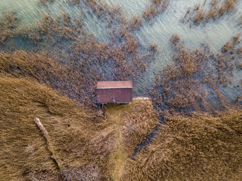 High angle view of small boat house on lake shore with reed in water