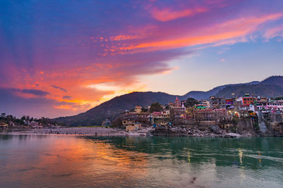 Houses by sea against sky during sunset