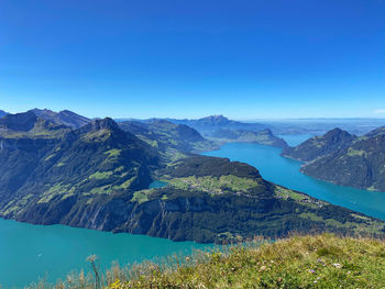 Scenic view of lake and mountains against clear blue sky