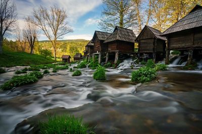 Surface level of water flowing by building against sky