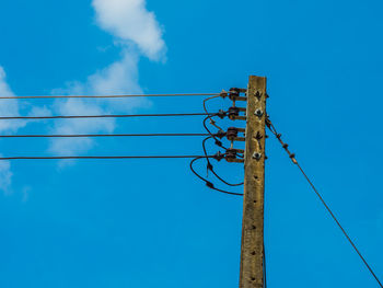 Low angle view of electricity pylon against blue sky