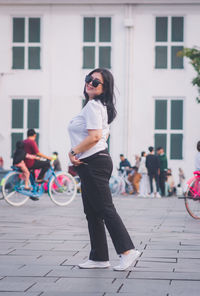 Full length of young woman standing against building