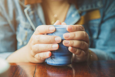 Cluse up an woman hands holding a cup of tea on a wooden table