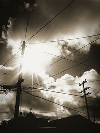 Low angle view of power lines against cloudy sky