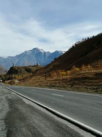 Road by mountains against sky